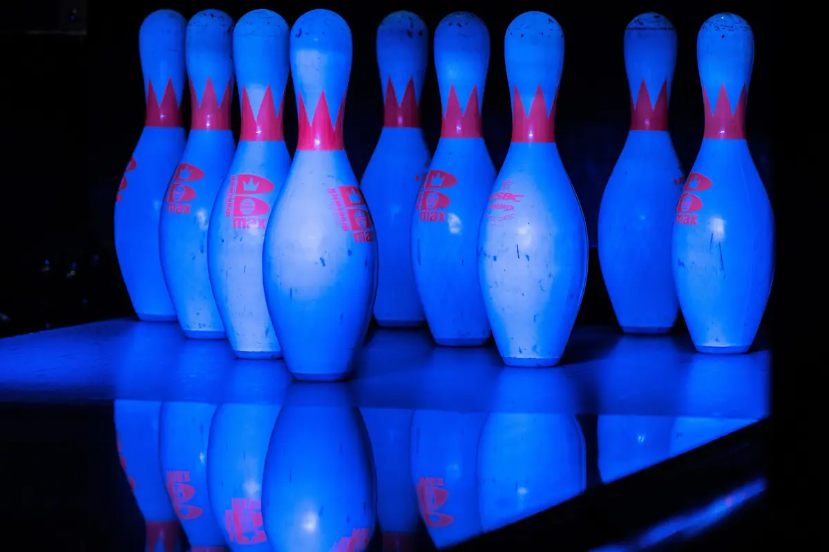 Bowling-Pins in blauem Licht auf spiegelnder Bahn